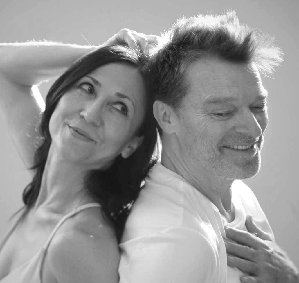 spirituelle-entertainer-ok-neu Pranayama und Breathwork Lehrer Jörg Buneru sitzt auf einer Yogamatte im Schneidersitz in einem hellen Yogastudio. Er blickt lächelnd in die Kamera, die Arme einladend geöffnet.